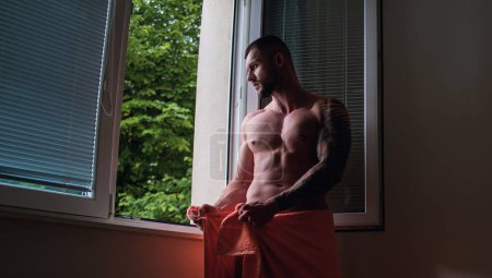 Téléchargez les photos : Handsome muscular man in bedroom on window curtains. Young handsome sexy man resting at home. Guy with athletic muscles. Sexy young handsome naked man on bedroom. Seductive gay - en image libre de droit