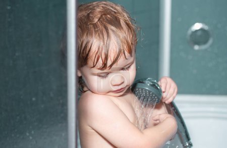 Téléchargez les photos : Bain d'enfant dans la salle de bain. Joyeux bébé drôle baigné dans le bain - en image libre de droit