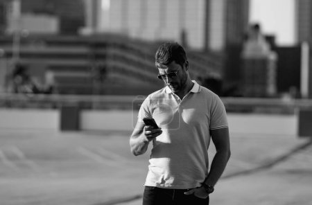 Casual handsome man chatting on phone in urban city. Well-dressed man talking on phone outdoor. Businessman using phone. Phone conversation in city. Outdoor fashion portrait