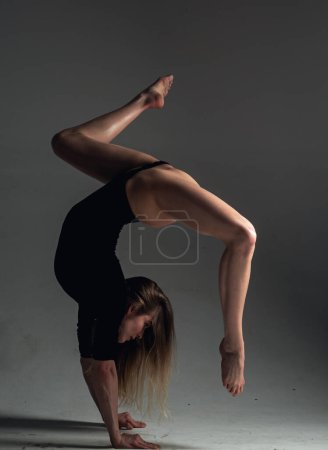 Photo for Flexible sexy body of young woman on black background. Sexy woman exercise. Fit slim sexy woman body in bodysuit. Sexy woman stretching with pose stretch. Fit fitness athlete stretches - Royalty Free Image