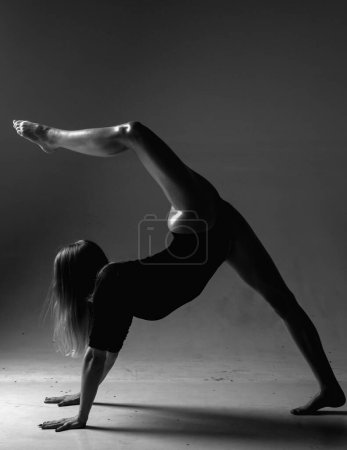 Photo for Flexible sexy body of young woman on black background. Sexy woman exercise. Fit slim sexy woman body in bodysuit. Sexy woman stretching with pose stretch. Fit fitness athlete stretches - Royalty Free Image