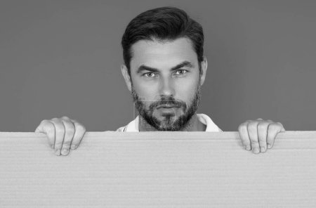 Photo for Man with empty blank banner ad on studio background. Portrait of attractive man holding empty blank poster. Man showing blank poster. Male presenting signboard, board or banner with copy space - Royalty Free Image