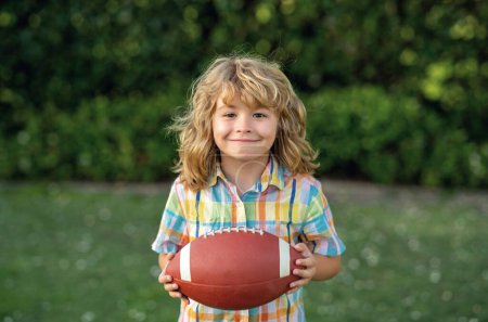 Photo for American boy playing a american football or rugby in park. Sporty kids. Boy with rugby ball. Football player holding game ball - Royalty Free Image