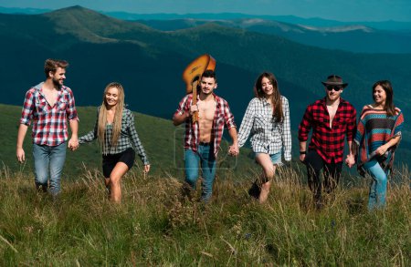 Photo for Company of young active friends of boys and girls hiking in mountain countryside. Summer music festival. Happy group of young girls and boys at music festival. Young men and women on camping - Royalty Free Image