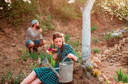 Téléchargez les photos : Couple de jardiniers avec outils de jardin. Amis travaillant dans le jardin. Jardinage agriculture et les gens concept - en image libre de droit