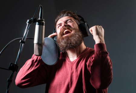 Cantante cantando rock. Cara de expresión de cerca. Productor de sonido grabando una canción en un estudio de música. Emocionado Karaoke