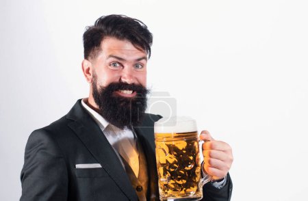 Foto de Hombre feliz en traje clásico bebiendo cerveza. Tipo barbudo en traje de negocios se ve feliz y satisfecho. Retrato del hombre con copa alta de cerveza levantada isoalted en blanco - Imagen libre de derechos