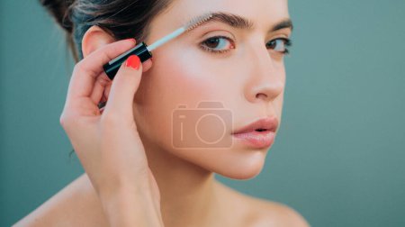 Care beauty eyebrow. Beautiful woman with brow brush in hand. Attractive sexy girl with glamorous professional nude makeup brushing up her perfect eyebrows with brush. Natural eyebrow makeup look