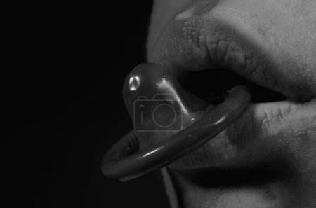 Foto de Condón. Mujer sosteniendo un condón en su boca. Concepto de sexo seguro. Jovencita sosteniendo condón en labios sensuales. Primer plano sexy encantadora dulce encantadora dama con la boca labios rojos morder condón - Imagen libre de derechos