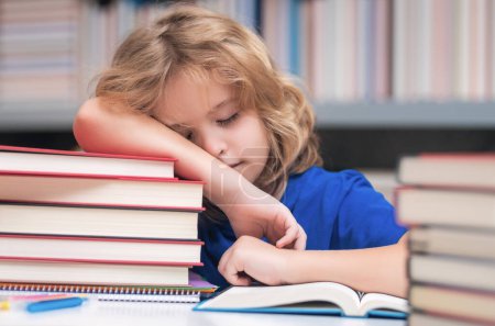 Photo for Tired and bored school boy. Child reads books in the library. Schoolkid with book in school library. Kids literature for reading. Learning from books. School education and clever talented pupil genius - Royalty Free Image