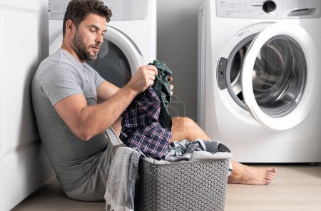 Photo for Man with clothes near washing machine. Laundry cleaning. Housework, homework, male housekeeper. Husband man doing laundry at home. Washer and dryer at home - Royalty Free Image