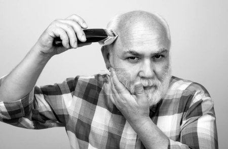 Senior Friseur Mann mit Haarschneidemaschine, Haarschnitt mit einem elektrischen Rasierer. Friseursalon-Konzept