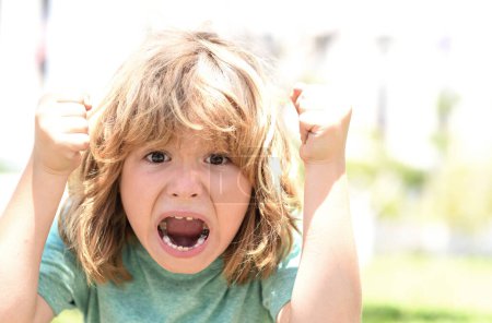 Photo for Kid boy temper with angry expression. Angry hateful little anger boy, child furious. Angry rage kids face close up. Anger hateful child with furious portrait. Boy fight with fist gesture punch - Royalty Free Image