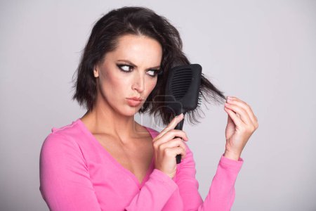 Photo for Young woman with hair loss problem worried about hairloss. Messy bed hair. Problem with tangled hair. Worried girl with damaged hair. Hairloss problem. Portrait of woman with a comb and bad hairs - Royalty Free Image