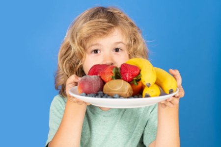 Téléchargez les photos : Assiette enfant drôle avec des fruits. Enfant avec des fruits et légumes. Aliments sains - en image libre de droit