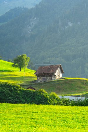 Photo for Alps home in mountains. Mountain green field alpine Mountains landscape nature with wooden old houses. Travel and hiking concept. Landscape with old buildings, high rocks. Mountains in Alps - Royalty Free Image