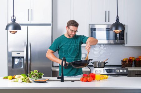 Photo for Man chef cooking food in pan pot in kitchen. Process of preparing gourmet dish. Man cooking at home in kitchen, using pot. Chef cooking food. Handsome chef cook cooking concept - Royalty Free Image