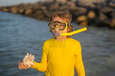 Foto de Vacaciones en playa. Un chico divertido usando una máscara de buceo de snorkel encontró un coral o concha en el agua del océano. Summer Kids Buceo de snorkel. El niño se sumerge en el agua. Vacaciones de verano - Imagen libre de derechos