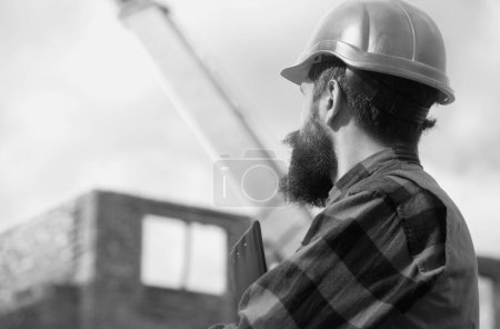 Téléchargez les photos : Travailleur de construction dans le casque posant sur le chantier de construction. Portrait du travailleur de la construction en plein air - en image libre de droit