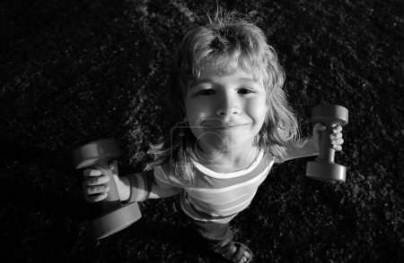 Foto de Un niño fuerte. Un niño gracioso con mancuernas. Concepto de salud infantil - Imagen libre de derechos