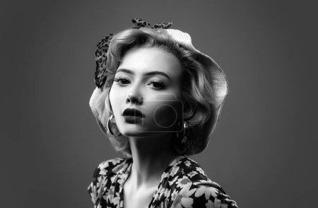Kaukasisches blondes Model posiert in Retro-Mode und Vintage-Konzeptstudio-Shooting. Pin up Frauenporträt. Schöne Retro-Hündin im Tupfen-Kleid mit roten Lippen und Maniküre-Nägeln und alter Mode