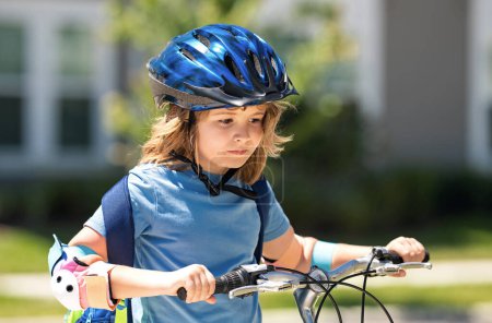 Enfant à vélo dans un casque. Enfant vélo d'équitation dans un casque de protection. Sécurité enfants sport et activité. Joyeux garçon en vélo dans le parc d'été. Casque de vélo, sécurité vélo, accessoires cyclistes
