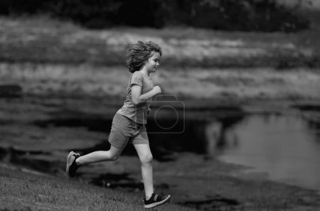 Foto de Mañana corriendo corriendo con niños. Corredor de niños corriendo en la naturaleza. Estilo de vida activo para niños sanos. Un chico deportivo corriendo por la calle. Deportivo niño corredor corriendo en parque - Imagen libre de derechos