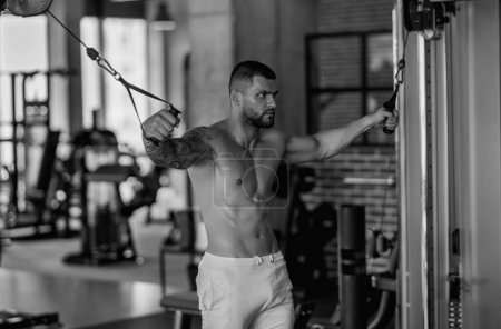 Téléchargez les photos : Musclé homme séance d'entraînement dans la salle de gym. Homme athlétique ayant un entraînement de poids dans la salle de gym. Beau homme avec des muscles forts séance d'entraînement dans la salle de gym. Portrait de mâle musclé sexy avec haltères. Exercice bodybuilder - en image libre de droit