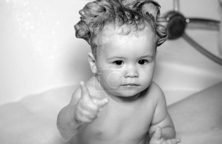 Téléchargez les photos : Il se baigne dans la salle de bain. Bains de bébé dans un bain avec mousse et bulles de savon - en image libre de droit