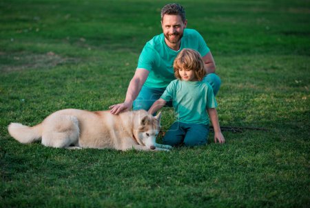Foto de Padre e hijo con perro en la naturaleza. Papá y el niño con perro mascota divertirse al aire libre. Niño niño paseo con perrito - Imagen libre de derechos