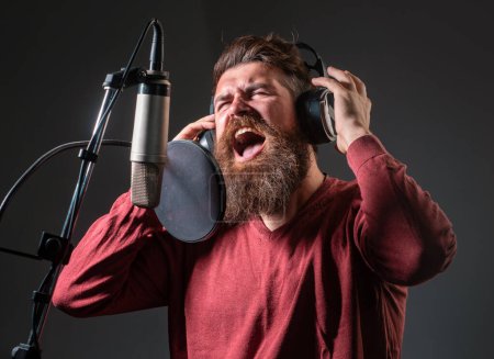 Sänger in einem Tonstudio. Ausdrucksstarker bärtiger Mann mit Mikrofon. Ausdruck aus nächster Nähe. Karaoke-Unterzeichner, Sänger