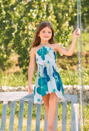 Photo for Cute little girl on a swing. Smiling child playing outdoors in summer. Happy kids swinging at the park. Happy kid having fun outdoors - Royalty Free Image