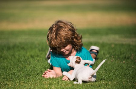 Téléchargez les photos : Enfant heureux et chien de compagnie jouant à la pelouse arrière-cour - en image libre de droit
