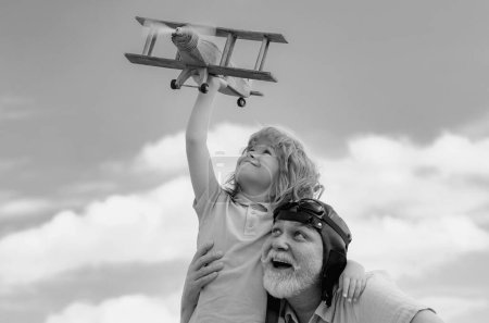 Grandfather and son enjoying play with plane together on blue sky. Family dream. Child dreams with plane. Grandfather and child son dream. Daydreamers. Dreams and imagination. Dreamy son