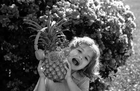 Foto de Niño sosteniendo piña sonriendo con cara feliz. Frutas de verano - Imagen libre de derechos
