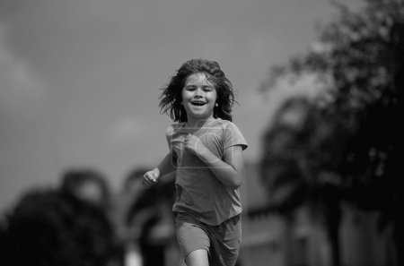 Foto de Niño corriendo en la calle de verano. El chico disfruta correr. Un chico corriendo por el vecindario. Los niños corren por la carretera urbana. Feliz infancia. Niño corriendo en el parque. Deportes y fitness, ejercicio para niños - Imagen libre de derechos