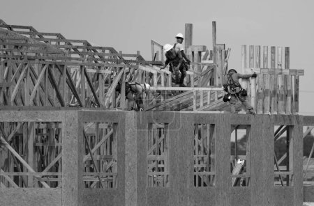 Photo for Roof repair on rooftop. Construction worker install new roof. Construction worker roofing on a large roof apartment building development. Roofer carpenter working on roof structure construction site - Royalty Free Image
