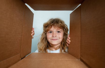 The surprised child unpacking, opening carton box and looking inside. The package, delivery, surprise, kids gift concept