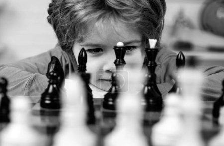 Téléchargez les photos : Petit malin qui pense aux échecs. Développement précoce des enfants. Fils joue aux échecs et sourit à la maison. Portrait gros plan, drôle de visage - en image libre de droit