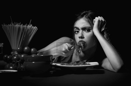 Photo for Young woman eating delicious pasta, enjoying tasty homemade spaghetti in kitchen interior. Pasta, Noodles, Linguine, Vermicelli. Sexy kitchen. Sexy woman on kitchen table. Kitchen menu. Italian food - Royalty Free Image