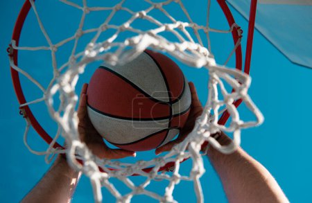 Foto de El baloncesto como símbolo deportivo y deportivo de una actividad de ocio en equipo. Baloncesto atravesando la canasta en el cielo - Imagen libre de derechos