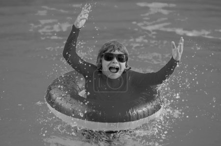 Foto de Niño con anillo inflable en piscina. Vacaciones de verano. Vacaciones de verano. Fin de semana de verano para niños. Niño en la piscina. Chico divertido en anillo inflable en aquapark - Imagen libre de derechos