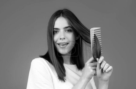 Photo for Woman is making hairstyle with comb. Beautiful young woman holding healthy and shiny hair, studio - Royalty Free Image