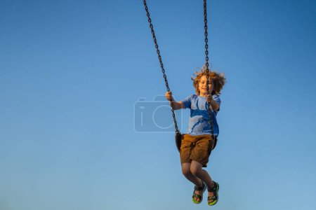 Photo for Joyful kid swinging on a swing. Happiness children. Child having fun on a swing outdoor. Craziness and freedom. Kid playing on swing-set outdoor. Playful child swinging very high to the sky - Royalty Free Image