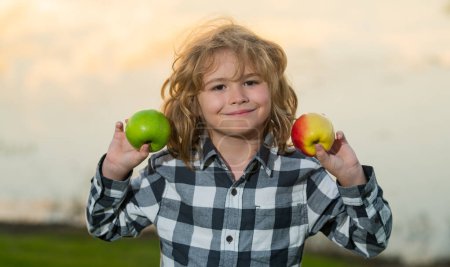 Foto de Niña manzana. Manzana fresca y madura para niños. Niño sosteniendo manzana, fondo del parque de verano. El chico come manzana verde. Retrato de un niño feliz y sonriente con manzanas. Alimento saludable - Imagen libre de derechos