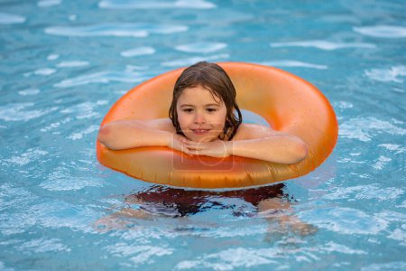 Foto de Niño feliz disfrutando de vacaciones de verano al aire libre en el agua en la piscina. Lindo niño pequeño en traje de baño nadar en un anillo inflable. Niño flotando en una piscina - Imagen libre de derechos