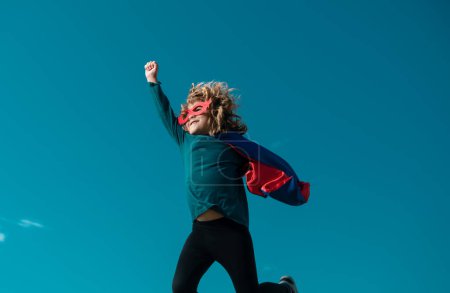 Téléchargez les photos : Super saut. Garçon en rouge super héros cape et masque volant. Liberté, enfance, mouvement et concept d'enfant - en image libre de droit