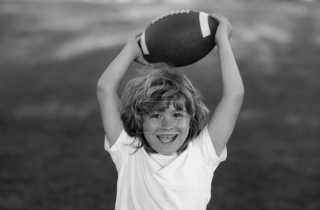 Photo for American style football. Kid boy having fun and playing american football on green grass park - Royalty Free Image