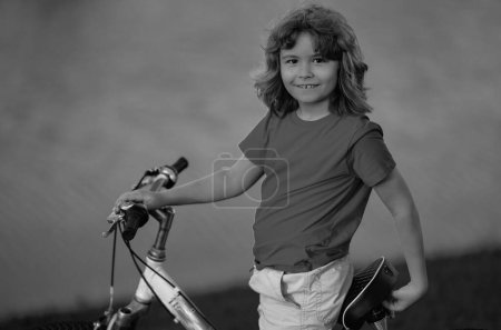 Little kid boy ride a bicycle in the park. Kid cycling on bicycle. Happy smiling child riding a bike. Boy start to ride a bicycle. Sporty kid bike riding on bikeway. Kids bicycle
