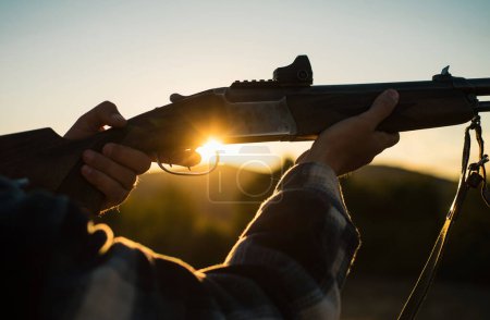 Gewehr Jäger Silhouette in schönen Sonnenuntergang. Patronenhülsen. zog den Abzug der Schrotflinte